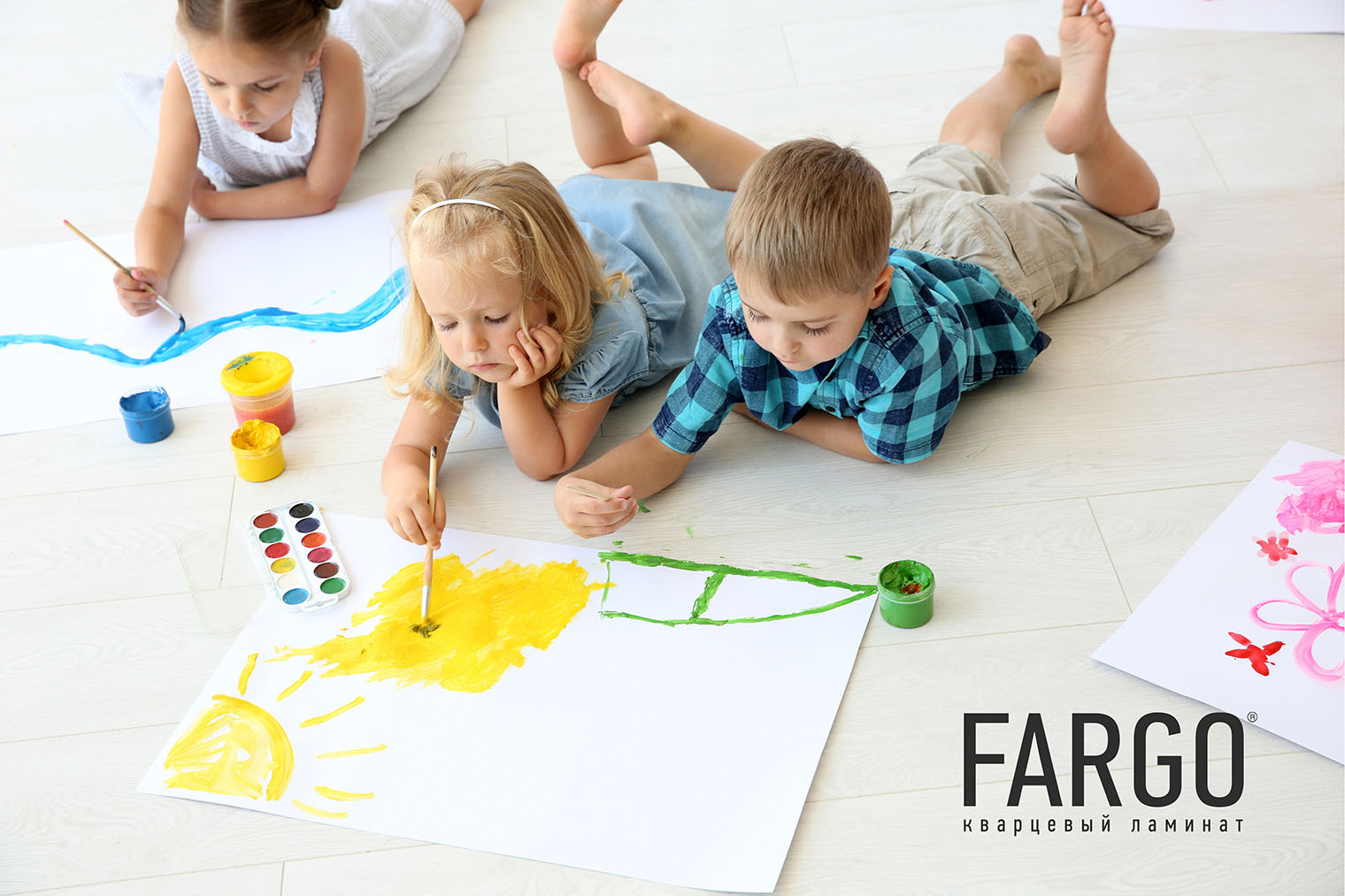 Трое детей лежат на светлом полу, рисуют красками, пачкая кварцевый ламинат в декоре под выбеленное дерево